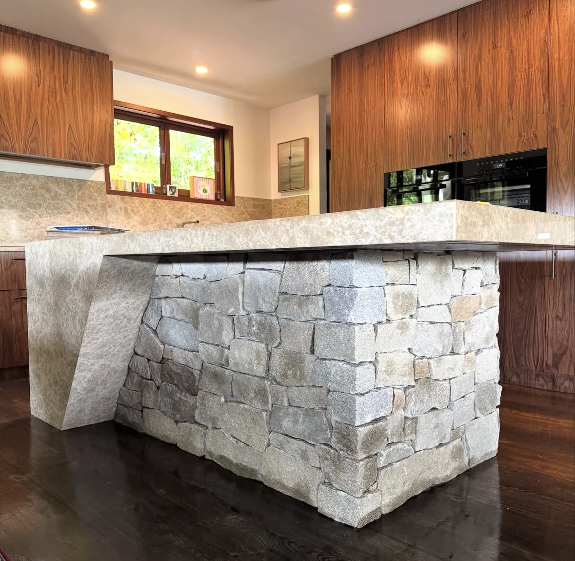 Natural stone kitchen island beneath a pale benchtop, with timber cabinetry